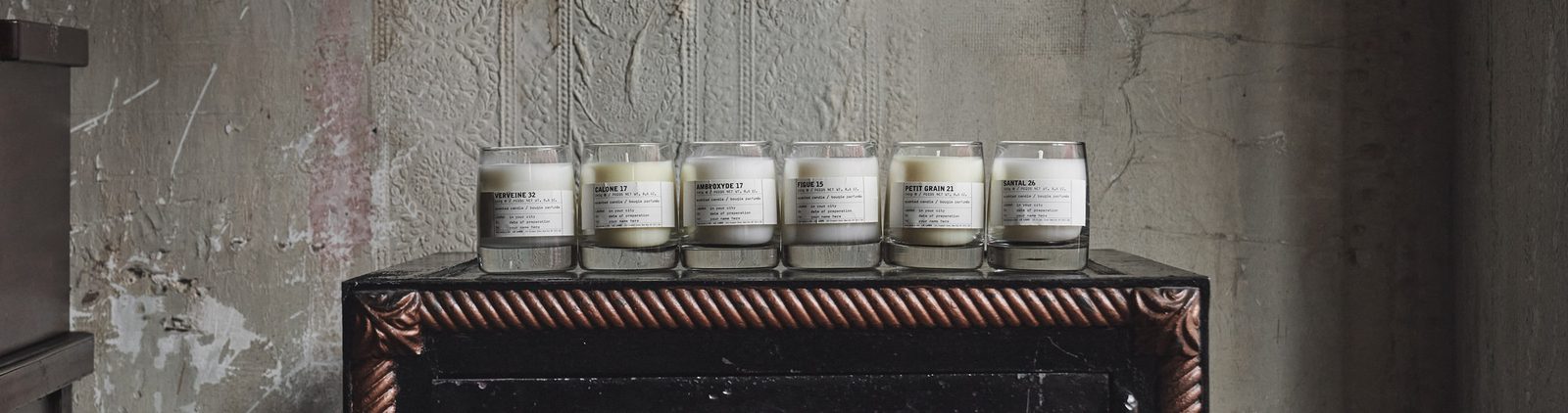 Le Labo classic candles lined up on a wooden dresser